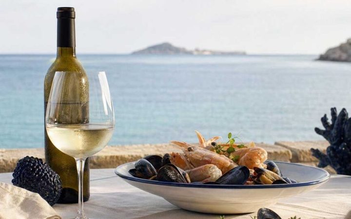 Demo Ristorante: piatto di crostacei e vino bianco con il mare sullo sfondo